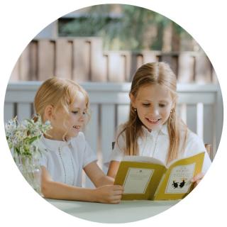 Zwei Mädchen lesen in einem Buch. Link zu unserem Onlineschaufenster Bücher für die Ferien.